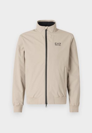 Beige lättviktsjacka med hög krage, framzipper, elastiska ärmar och sidofickor. Har EA7-logotypen tryckt i svart på bröstet.