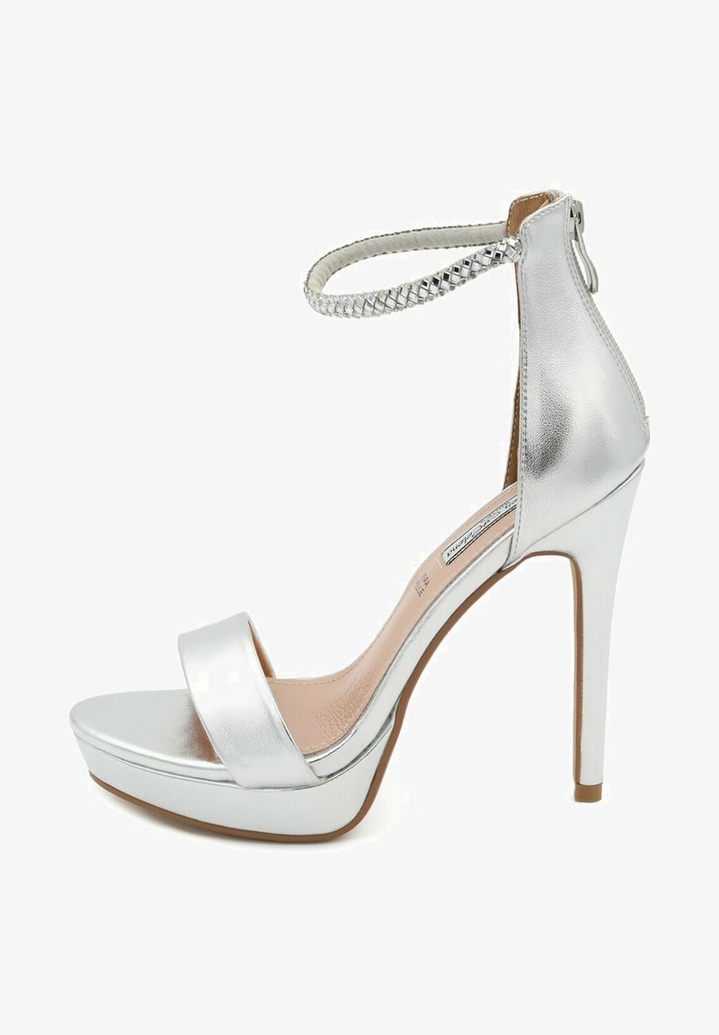 Sandalo argentato con tacco alto e cinturino alla caviglia, fascia frontale spessa, finitura metallica lucida e suola platform per maggiore altezza e comfort.