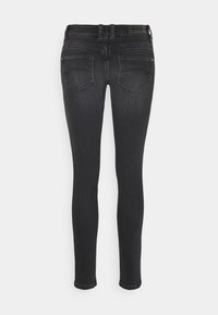 Jeans ajustados en denim de lavado oscuro. Con cintura de media altura, dos bolsillos traseros con costuras sutiles y un dobladillo limpio. Sin embellishments visibles.