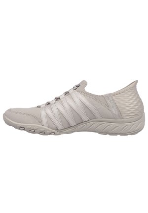Lysegrå slip-on sneaker med krydsede elastiske remme, tekstureret hæl og fleksibel sål designet til komfort og afslappet brug.