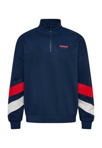 Pullover in pile blu navy con colletto alto e zip a metà. Presenta strisce diagonali rosse, bianche e blu lungo le maniche. Logo Hummel in rosso.