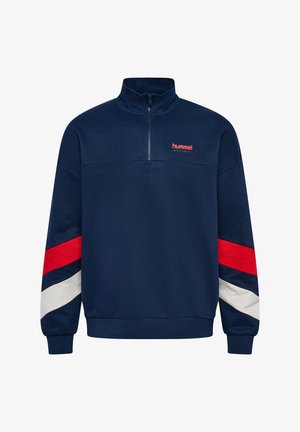 Pullover in pile blu navy con colletto alto e zip a metà. Presenta strisce diagonali rosse, bianche e blu lungo le maniche. Logo Hummel in rosso.
