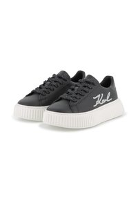 Black leather sneakers with a thick white rubber sole, featuring sparkling black laces and white "Karl" embroidery on the side.