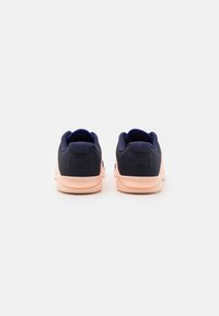 Scarpe sportive di colore blu scuro con un retro testurizzato, suola in gomma rosa e colletto imbottito; presenta un dettaglio con logo sul tallone.