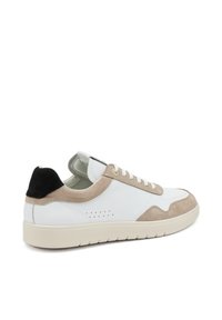 Sneaker bianco in pelle con dettagli in suede beige, punta tonda, design con lacci e un tab sul tallone nero. Suola in gomma testurizzata con scanalature.