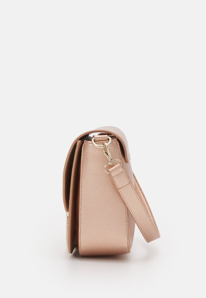 Sac à main en cuir texturé couleur rose doré avec une forme structurée, une bandoulière réglable et un fermoir en métal doré. La vue de côté met en valeur la profondeur et le design.