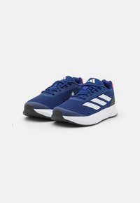 Le scarpe da corsa in rete blu navy presentano strisce bianche sui lati, un colletto imbottito e una suola in gomma nera con un sottopiede bianco liscio.