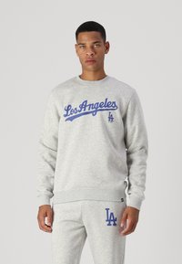 Gray sweatshirt with blue "Los Angeles" script and "LA" logo. Crew neck, ribbed cuffs, and waistband. Paired with matching gray pants.