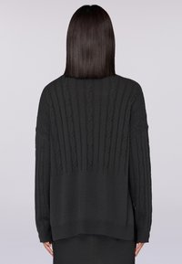 Maglione nero lavorato a maglia con una texture a coste, caratterizzato da dettagli a trecce e maniche lunghe. L'orlo è leggermente più lungo sul retro.