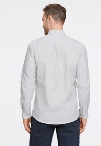 Camisa de manga larga para hombres en gris claro con finas rayas verticales. Presenta un cuello clásico, puños con botones y un dobladillo sutilmente curvado.