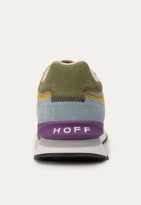 Scarpa da ginnastica multicolore con tomaia in suede azzurro chiaro, dettagli verdi e gialli, logo bianco e dettaglio viola sul tallone. Presenta una suola esterna testurizzata.