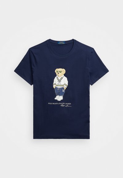 Navy blauwe katoenen t-shirt met een berenafbeelding in sportieve kleding met een zonnebril, vergezeld van merktekst en handtekening in het wit.