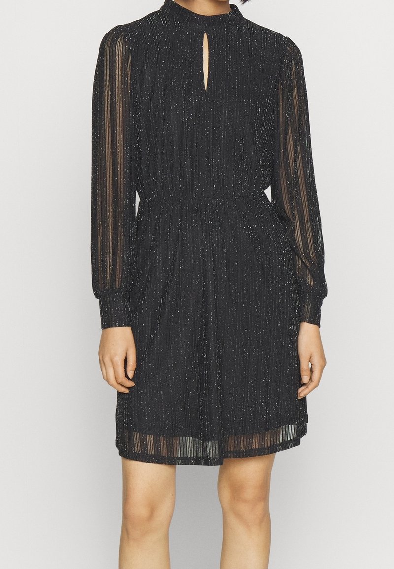 Robe noire mi-longue avec des manches longues transparentes, des rayures scintillantes subtiles, une taille froncée et un petit détail en forme de trou de serrure au niveau du col.