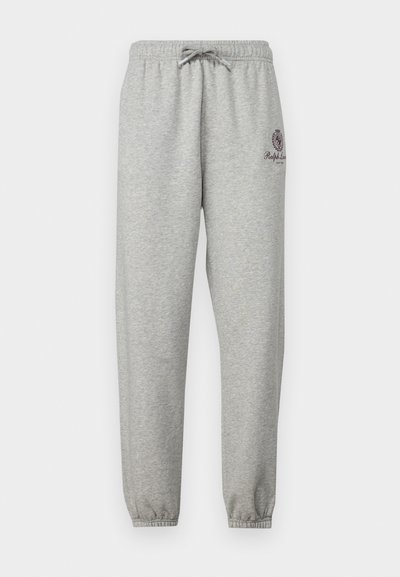 Pelēki treniņbikses ar auklu jostasvietā, elastīgām piedurknēm un emblēmu kreisajā pusē. Izgatavotas no mīksta, tekstūrēta auduma.