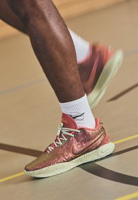 Nike basketballsko har en skinnende, metallisk roseguld overdel med orange accenter, hvide snørebånd og en struktureret mintgrøn sål.