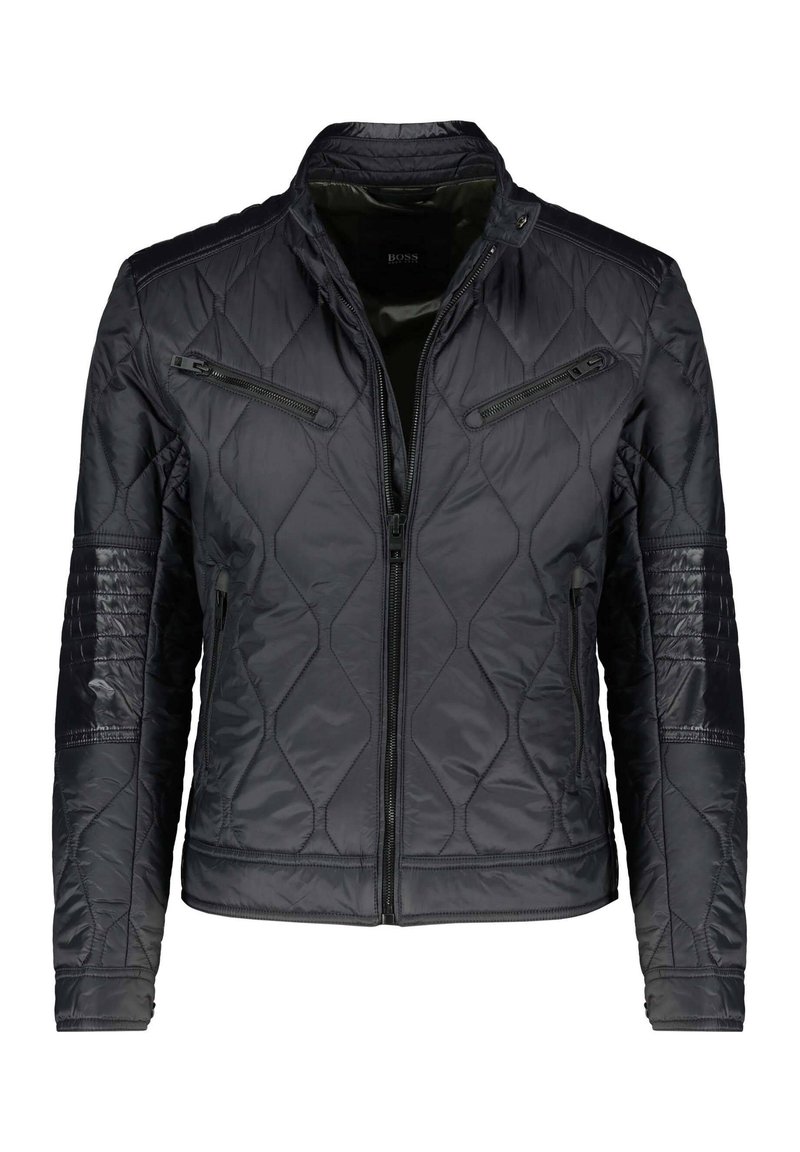 Mustat vuoratut takit, jossa on pystykaulus, vetoketjulliset taskut sekä teksturoidut olka- ja hiho-paneelit. Valmistettu kevyestä, kiiltävästä kankaasta.