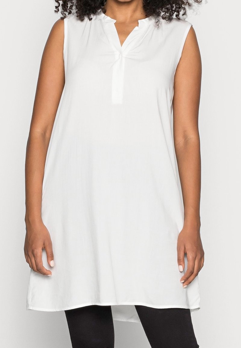 Túnica blanca sin mangas con escote en V, tapeta con botones y dobladillo recto. Hecha de tela ligera, que ofrece una textura suave.