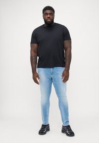 Black short-sleeve t-shirt, light blue slim-fit jeans, and black sneakers with purple accents. Simple design with a relaxed fit.