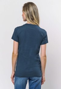 Kratka majica tamnoplave boje s okruglim izrezom, uskim krojem i glatkom teksturom pamuka, prikazana s leđa.