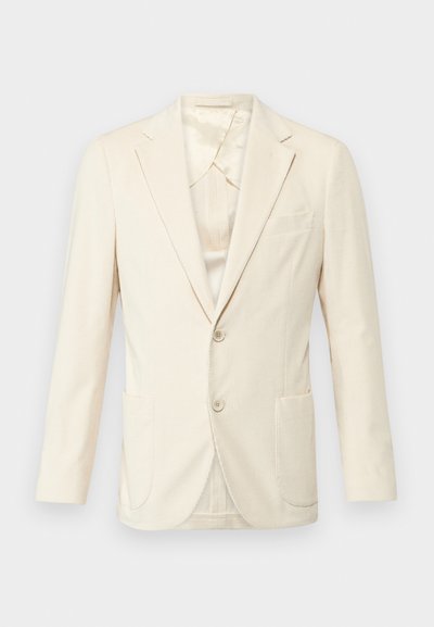 Bežs žakets ar strukturētu audumu, vienrindas dizains, divas priekšējās kabatas un ar ielocītiem uzlādes galiem. Iekšpuse ar vieglu spīdumu.