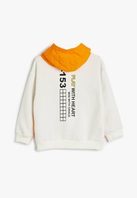 Sudadera crema con capucha naranja. Presenta texto negro y elementos gráficos en la parte posterior. Textura suave, mangas largas y puños acanalados.