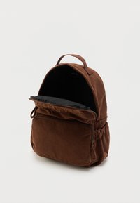 Καφέ σακίδιο πλάτης από κορδόνι με μπροστινή τσέπη με φερμουάρ, πλευρικές ελαστικές τσέπες και χειρολαβή στην κορυφή, εμφανιζόμενο μερικώς ανοιχτό σε λευκό φόντο.