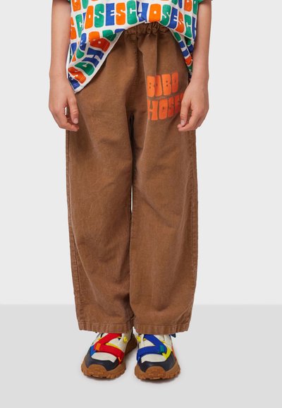 Brown corduroy wide-leg pants with an orange "BOBO HOSE" print. Worn with multi-colored sandals featuring red, blue, and yellow straps.