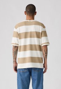 Beige and white striped short-sleeve shirt in a relaxed fit, made of soft material. Cotton fabric has a smooth texture and clean design.