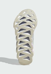 Sneaker con suola intagliata e testurizzata in off-white, dotato di un intricato motivo geometrico e dettagli grigio chiaro nella parte superiore.