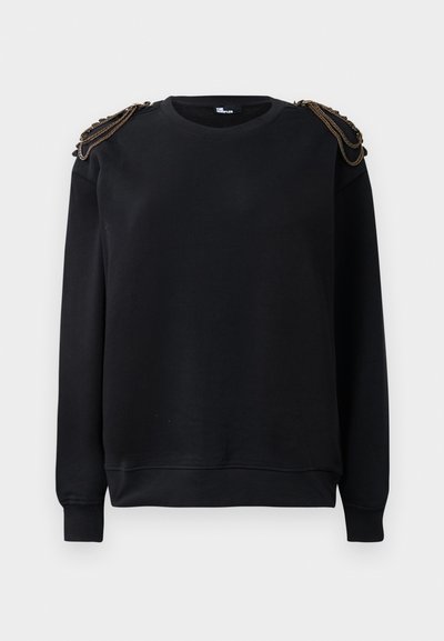 Czarna bluza z długimi rękawami, okrągłym dekoltem i skomplikowanymi detalami łańcuchowymi na ramionach. Miękka tekstura i luźny krój.