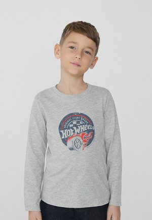 Langärmliges graues Shirt aus Baumwolle mit einem runden roten und blauen "Hot Wheels"-Grafikdesign, das ein Reifen- und Flammenmotiv zeigt.
