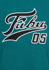 Törökzöld kapucnis pulóver V-nyakkal, nagy fekete-fehér "Fubu" felirattal és blokk betűtípussal írt "05"-tel. Kanguru zsebet tartalmaz.