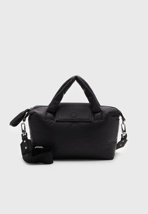 Sac à main en tissu noir doux avec de courtes poignées et une bandoulière amovible sur un fond clair uni.