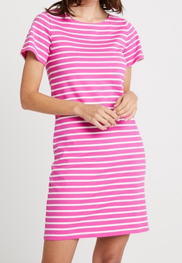 Femme portant une robe à manches courtes, rayée horizontalement rose et blanche, longueur aux genoux, debout sur un fond uni.