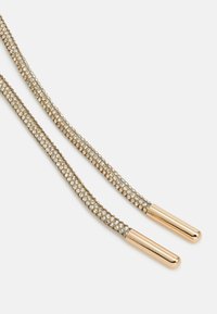 Rhinestone-prydde snorer i gulltoner med glatte metallender, preget av et strukturert, sammenflettet design og skinnende detaljer.