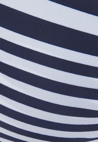 Tkanina v mornarsko modri in beli barvi s horizontalnimi črtami, ki se ponaša s splošno gladko teksturo in enakomerno razporejenim vzorcem.