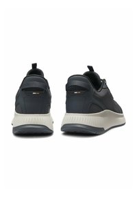 Black athletic shoes with a textured mesh upper, padded collar, and light gray rubber sole; features subtle branding accents.