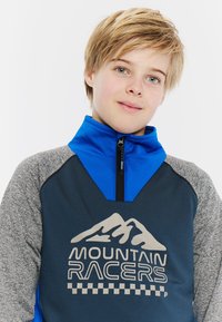 Sudadera de forro polar con cuello azul y mangas grises. Presenta un cuerpo de color azul oscuro con "MOUNTAIN RACERS" y un gráfico de montaña en plata. Cuello con cremallera.