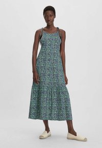 Midi-Kleid mit Blumenmuster und verstellbaren Bindeträgern, mit einem Rüschensaum. Das Muster enthält lila und grüne Farbtöne auf einem dunklen Hintergrund.