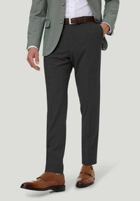 Kohlegraue Hosen mit Slim-Fit-Schnitt, strukturierter Stoff und Seitentaschen, ergänzt durch braune Lederschuhe und ein hellgrünes Blazer.
