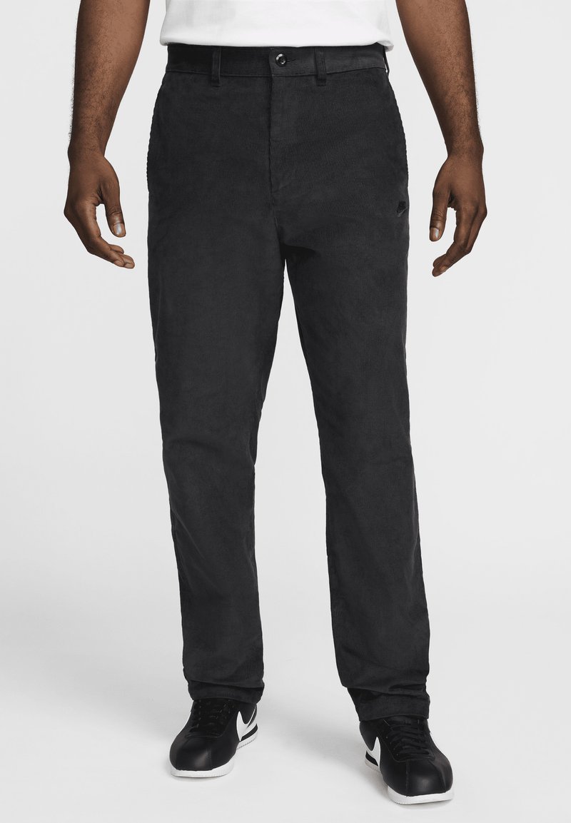 Svarta kordbyxor med rak passform, med knäppning, sidofickor och en mjuk textur. Bärs med svarta sneakers.