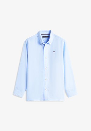 Svetle modrá košile s dlouhými rukávy, zapínáním na knoflíky, špičatým límečkem a malým vyšívaným logem na hrudi.