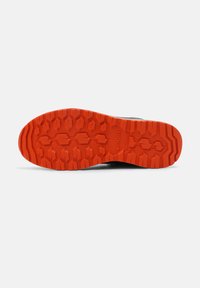 Schwarze Schuhsohle mit tiefen Profilen und einem leuchtend orangen Muster, das hexagonale Formen für Traktion und eine strukturierte Oberfläche aufweist.