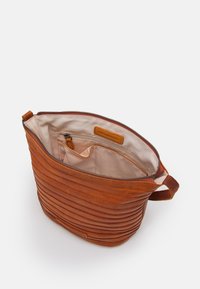 Bruine leren tas met een verticaal geribbelde structuur, ritssluiting en stoffen voering. Voorzien van een binnenzak en een handvat voor gemakkelijk dragen.