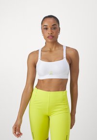Sutien sport alb, confecționat dintr-un material elastic, având bretele ajustabile, o talie ribbată și un mic accent galben în centru.