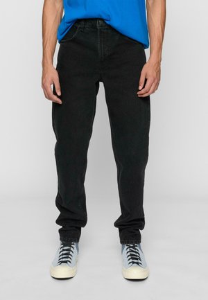 Svarte denimjeans med rett benpassform, fem-lommers design og subtil tekstur, sammen med lyseblå sneakers og en blå T-skjorte.