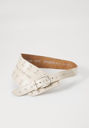 Cintura in pelle beige rivestita con borchie metalliche argentate e fibbia rotonda argentata, distesa in piano con il lato interno visibile su uno sfondo bianco.