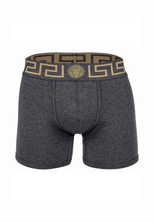 Dark gray boxer shorts with a gold and black Greek key patterned elastic waistband featuring a central emblem. Soft fabric texture.