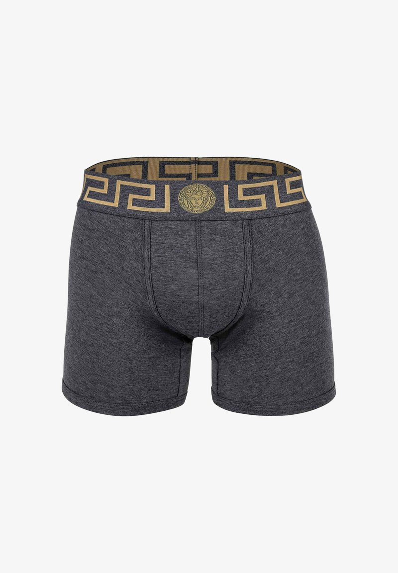 Dark gray boxer shorts with a gold and black Greek key patterned elastic waistband featuring a central emblem. Soft fabric texture.