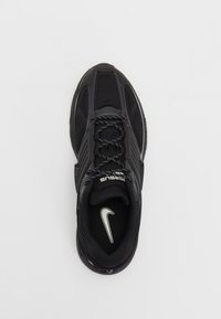 Baskets de sport noires avec une tige en mesh et synthétique, lacets noirs et blancs, et logo Nike blanc à l’intérieur du talon.